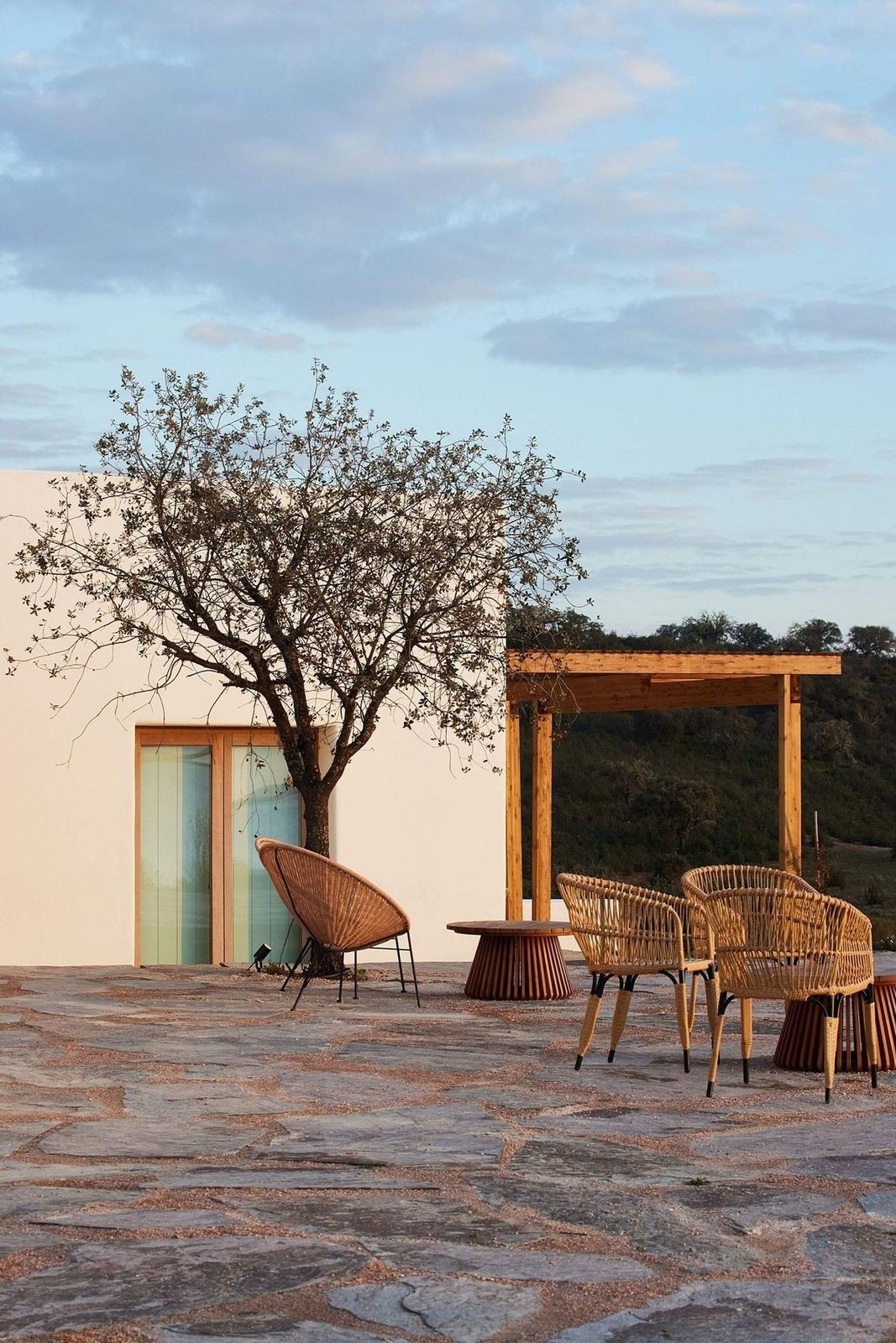 A whitewashed quinta and a lone tree on a stone terrace at dusk, Alentejo