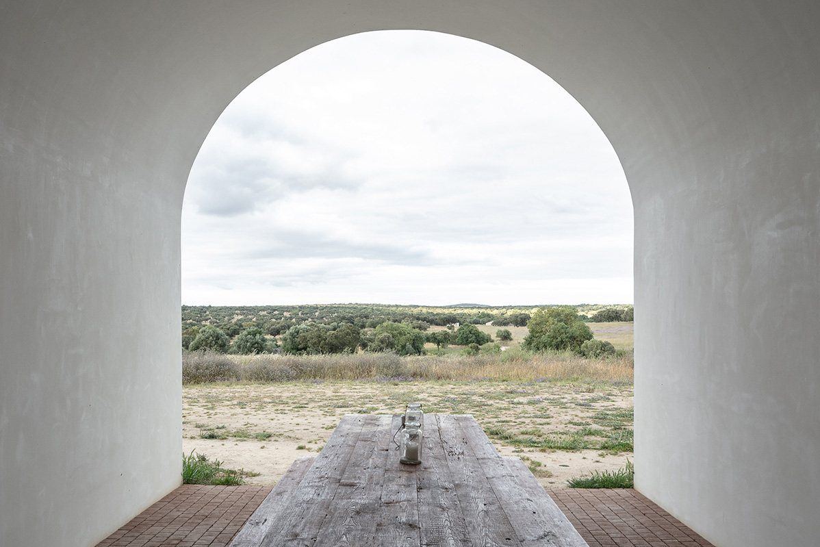 A whitewashed arch framing the plain and a long table, Alentejo